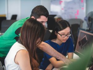 A diverse team collaborating around a laptop in a modern office, representing app development partnership